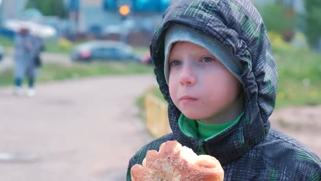 Junge-auf-der-Straße-eine-Brötchen-zu-essen.