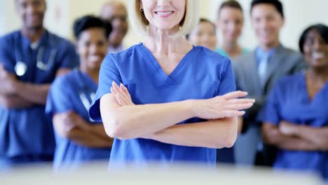 Portrait-of-female-nurse-and-team-of-staff