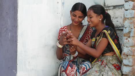 Zwei-indische-Frauen-Kleid-bunt-Freunde-lachen-und-Anteil-Foto-video-Geheimnisse-Liebe-am-Telefon-Kampf-Gerangel-und-Show-And-Tell-kommunizieren-Vortrag-besprechen-statisches-Bild-zwei-mittlere-Schuss-Treppe-Backsteinhaus