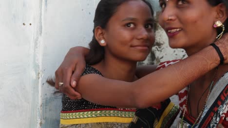 Two-girlfriends-share-support-hug-embrace-love-family-sister-best-friends-help-smile-laugh-together-bonding-closeup-static-camera-home-interior-Rajasthan-India-village-Asian-colorful-dress-costume