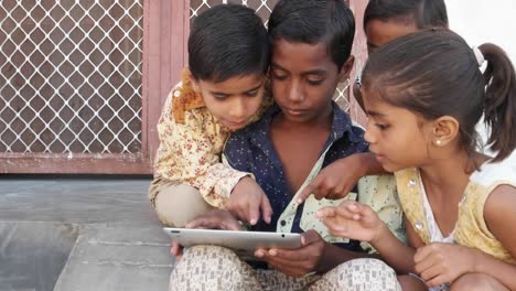 Kids-busy-on-a-touchscreen-tablet,-elder-sibling-teaching-them,-close-up-handheld