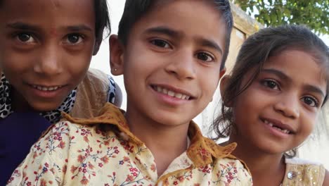 Three-Indian-kids-looking-at-the-camera-and-making-hand-gestures,-closeup-handheld