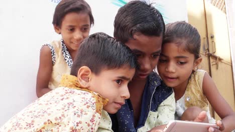 Indian-kids-sharing-a-touch-screen-phone-mobile-screen,-handheld