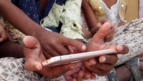 Indian-kids-sharing-a-touch-screen-phone-mobile-screen,-handheld-closeup