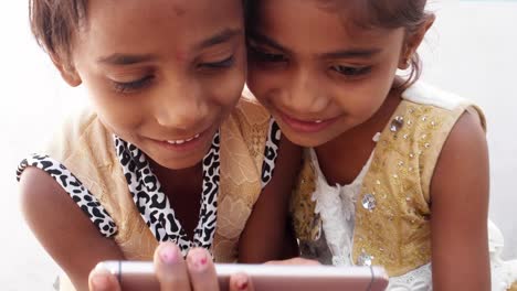 Two-Indian-girlfriends-watching-funny-video-on-a-touchscreen-device-together,-handheld