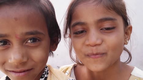 Two-kid-sisters-pointing-their-fingers-at-the-camera,-happy-and-smiling