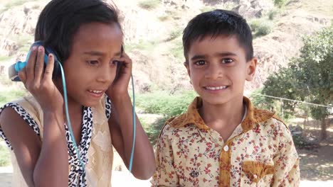 One-kid-listening-to-music-on-headphone-while-the-other-holds-the-cell-phone-mobile