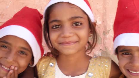 Closeup-mano-pan-en-cuatro-niños-sonrientes-con-sombreros-de-Santa-en-al-aire-libre-en-verano