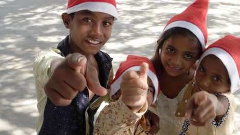 Top-shot-of-kids-with-Santa-hats-point-to-the-camera