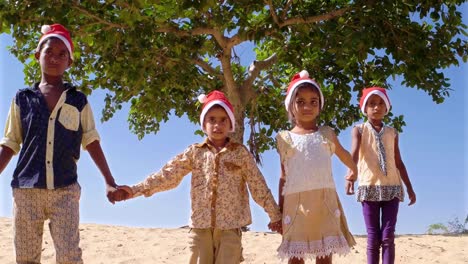 Breite-Schuss-aus-einer-Gruppe-von-jungen-Kinder-Hand-in-Hand-und-springen-und-spielen-im-Wüstensand