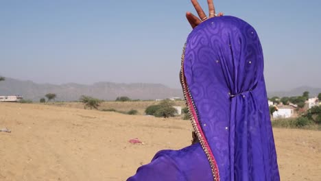 Nomadic-woman-dances-on-a-sand-dune-in-Rajasthan-with-camels-in-the-background