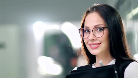 Low-angle-pretty-successful-businesswoman-putting-on-glasses-enjoying-break-standing-in-office