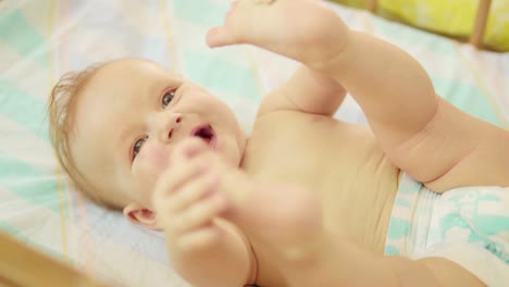 beautiful-newborn-lying-on-back-looking-into-camera-and-smiling