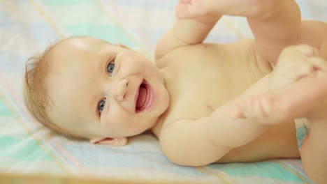 beautiful-newborn-lying-on-back-looking-into-camera-and-smiling