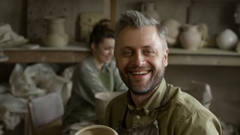 Happy-Male-Artisan-Posing-in-Pottery-Workshop