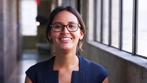 Young-businesswoman-wearing-glasses,-turns-to-camera,-laughs