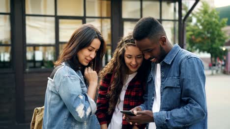 Happy-male-and-female-tourists-multiethnic-group-are-taking-selfie-standing-in-the-street-then-watching-photographs-and-laughing.-Tourism,-technology-and-fun-concept.