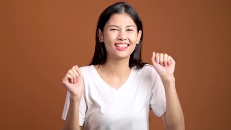 Junge-Frau-tanzen-isoliert.-Asiatische-Frau-im-weißen-T-shirt-tanzen-lustig-über-Orangen-Hintergrund.