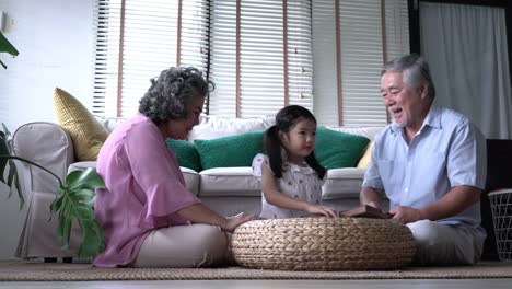 Couple-senior-and-kids-girl-playing-puzzle-games-together-in-living-room-at-home.-Concept-of-caucasian-family,-education,-growing-learn-and-development-of-age.-4k-resolution.