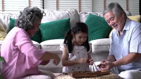 Couple-senior-and-kids-girl-playing-puzzle-games-together-in-living-room-at-home.-Concept-of-caucasian-family,-education,-growing-learn-and-development-of-age.-4k-resolution.