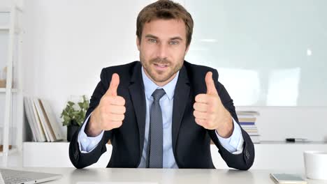 Thumbs-Up-by-Businessman-Looking-at-Camera-in-Office