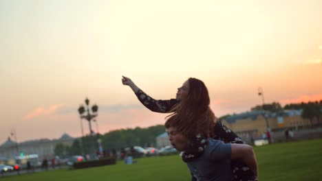 Happy-couple-playing-in-the-summer-field.-Riding-like-on-a-horse