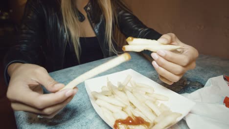 Portrait-of-girl-having-fun-making-funny-faces-while-eating-French-fries-playing-with-food