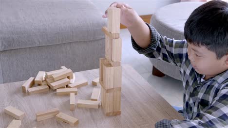 Chico-asiatico-jugando-con-juego-de-bloques-de-madera-en-casa.