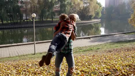 Junge-Mutter,-die-Spaß-mit-ihrem-Sohn-im-Herbst-Park-am-sonnigen-Tag