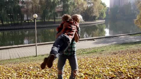 Joven-madre-divirtiéndose-con-su-hijo-en-el-Parque-otoño-en-día-soleado