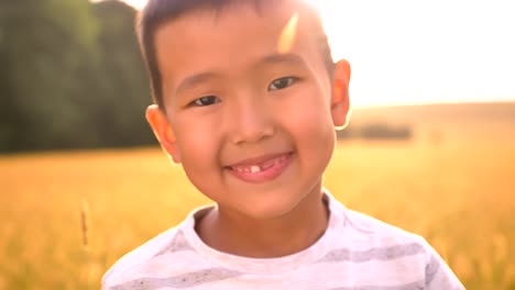 Shining-vibes-around-portrait-of-happy-asian-kid-in-sun-lights-on-wheat-field-on-countryside