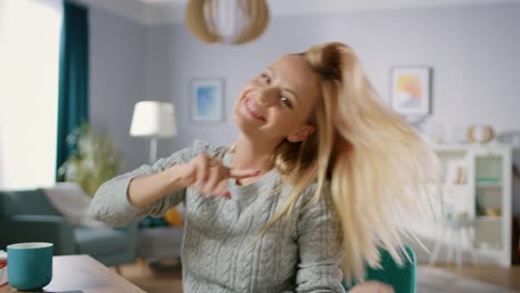 Beautiful-Cheerful-Blonde-Does-Funny-Dance-Routine-while-Sitting-at-Her-Desk-in-the-Living-Room.-Happy-Woman-Doing-Celebratory-Dancing.