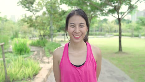 Healthy-beautiful-young-Asian-runner-woman-feeling-happy-smiling-and-looking-to-camera-after-running-on-street-in-urban-city-park.-Lifestyle-fit-and-active-women-exercise-in-the-city-park-concept.