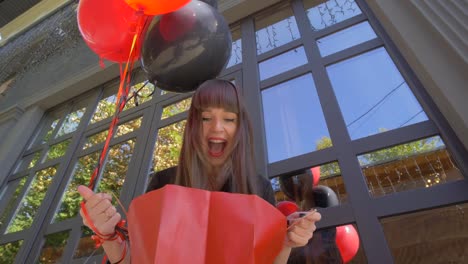 Shopping-junge-Frau-erstaunt-schauen-in-Papiertüte-und-glücklich-lächelt-vor-schwarzem-Hintergrund-mit-Luftballons