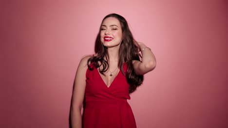 Morena-mujer-feliz-riendo-con-confeti-en-vestido-del-desgaste-rojo-fondo-rosa