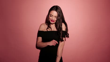 Brunette-happy-woman-laughing-with-confetti-in-pink-background-wear-red-dress