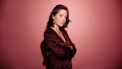 Brunette-happy-woman-upset-and-mad-on-someone.-Pink-background-wear-red-dress