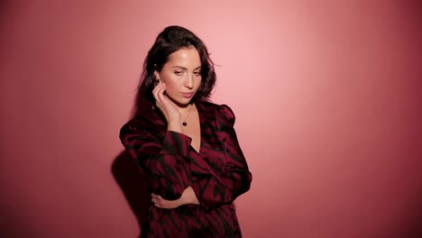 Brunette-happy-woman-upset-and-mad-on-someone.-Pink-background-wear-red-dress