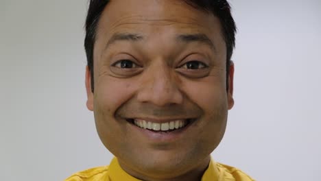 Close-up-of-an-Indian-man-looking-away-then-turning-and-looks-at-camera-and-smiles-a-toothy-smile