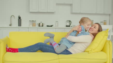 Carefree-mom-and-daughter-having-fun-on-sofa