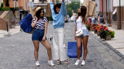 Glückliche-multirassische-Mädchen-mit-Einkaufstüten-im-freien