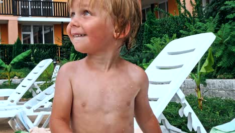 Happy-little-boy-sitting-near-the-pool