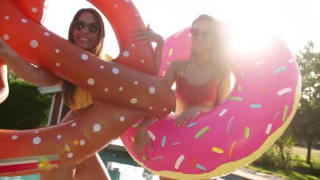 Girls-joking-around-with-novelty-pool-inflatables-with-sunflare