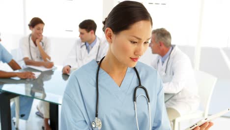 Happy-nurse-looking-at-camera-with-staff-behind-her