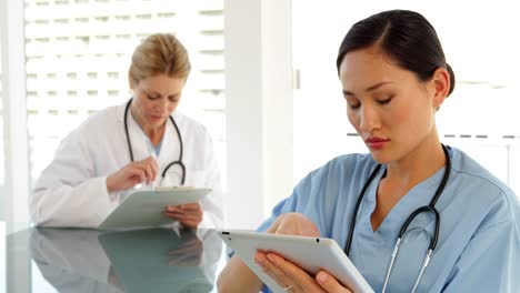 Medical-workers-sitting-at-desk-using-tablet