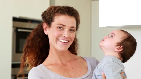 Mother-holding-her-happy-baby-boy-smiling-at-camera