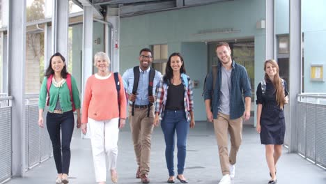 Group-of-smiling-teachers-walk-in-a-corridor-towards-camera