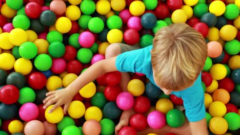 Niño-atractivo-jugando-y-divertirse-en-la-piscina-de-pelotas