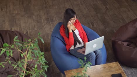 Mujer-asiática-en-loft-sentado-en-una-silla-del-bolso-de-haba