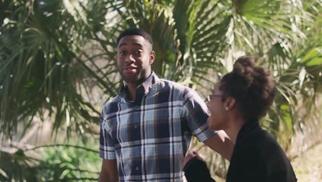 African-American-couple-posing-for-a-picture-in-front-of-a-palm-tree-and-swatting-a-fly-away